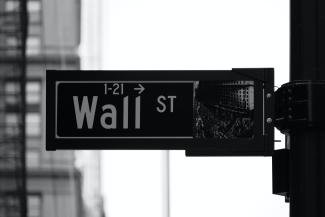 grayscale photo of Wall St. signage by Patrick Weissenberger courtesy of Unsplash.